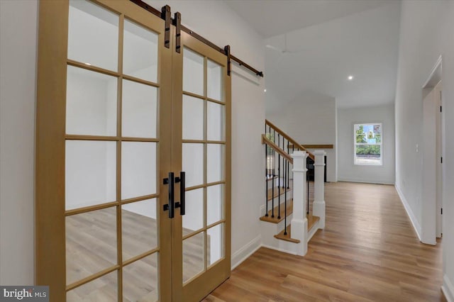 foyer entrance with light wood-type flooring, a barn door, and french doors