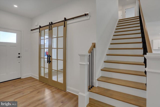 entrance foyer with a barn door, french doors, and light wood-type flooring