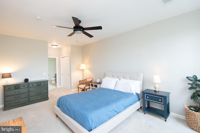 bedroom with light colored carpet, a closet, ceiling fan, and ensuite bath