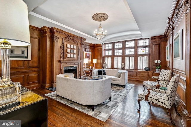 living room with dark hardwood / wood-style floors, crown molding, an inviting chandelier, and a raised ceiling