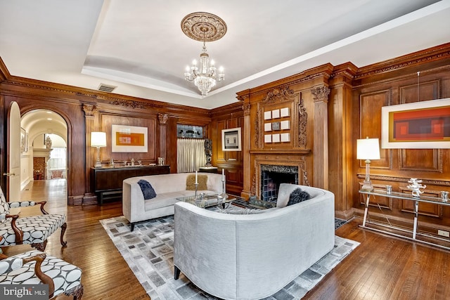 living room featuring dark hardwood / wood-style floors, an inviting chandelier, a raised ceiling, and a fireplace