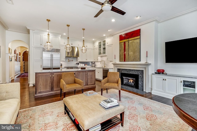 living room with ceiling fan, crown molding, sink, and dark wood-type flooring