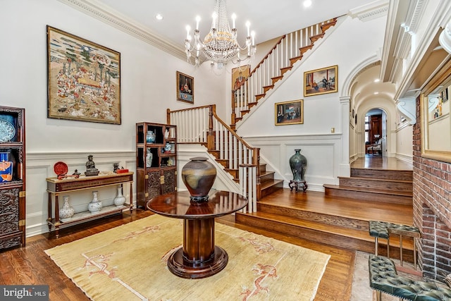 entrance foyer featuring crown molding, dark hardwood / wood-style flooring, a notable chandelier, and a high ceiling