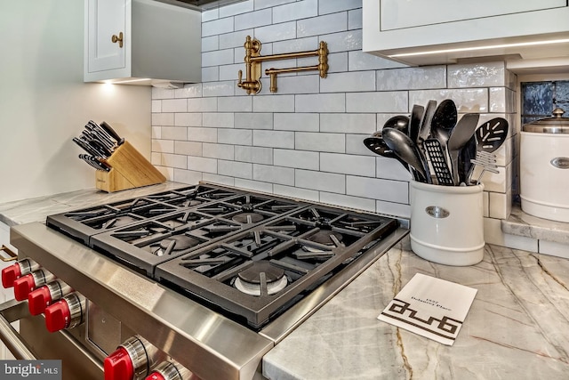 kitchen featuring high end stove, white cabinets, light tile flooring, and tasteful backsplash