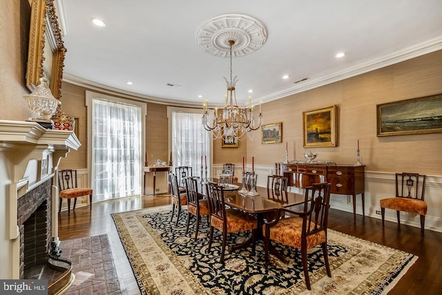 dining area with crown molding, dark hardwood / wood-style flooring, a notable chandelier, and a fireplace