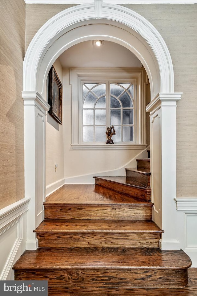 staircase featuring decorative columns and dark hardwood / wood-style floors