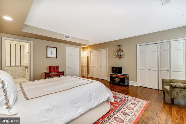 bedroom featuring two closets and dark hardwood / wood-style floors