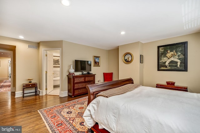 bedroom with connected bathroom and dark wood-type flooring