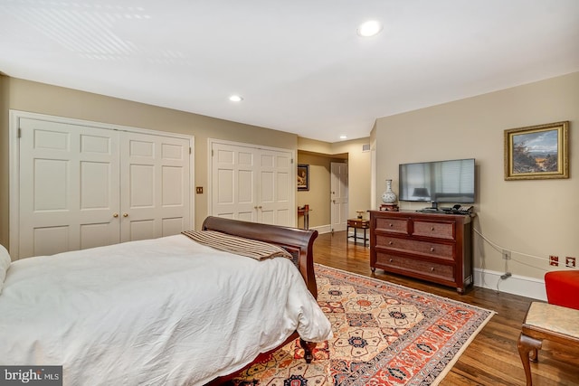 bedroom with dark hardwood / wood-style floors and two closets