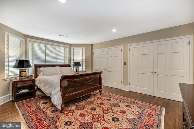 bedroom with dark hardwood / wood-style flooring and multiple closets