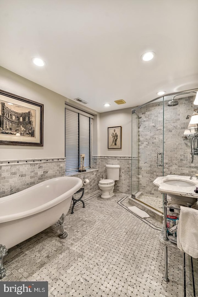 bathroom with separate shower and tub, toilet, tile floors, and tile walls