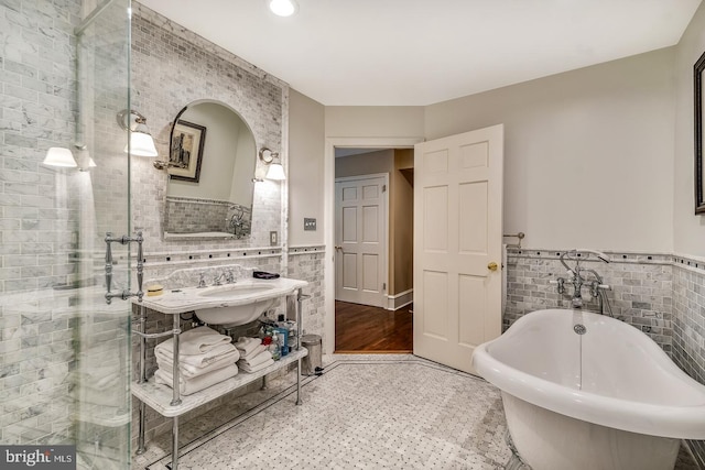 bathroom with tile walls, tile flooring, a washtub, and sink