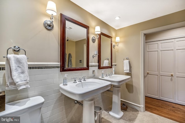 bathroom featuring backsplash, toilet, hardwood / wood-style floors, and tile walls