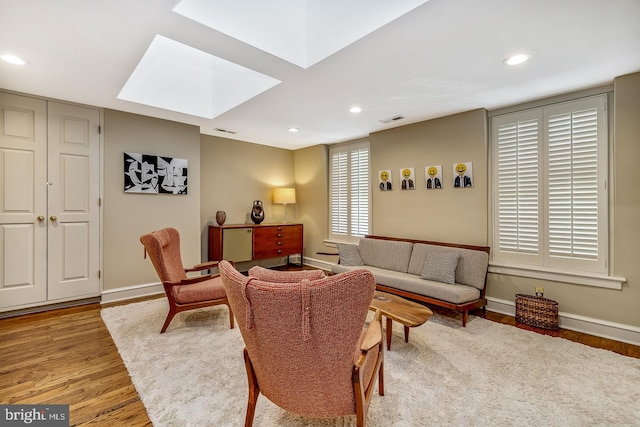 living room featuring a skylight and light hardwood / wood-style floors