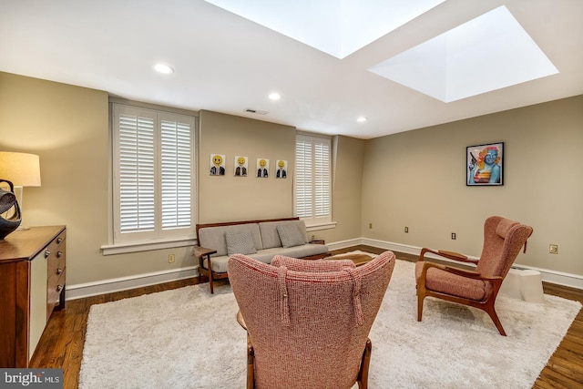 living room with a skylight and dark hardwood / wood-style floors