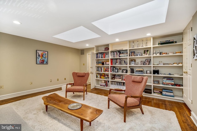 sitting room with a skylight and dark hardwood / wood-style floors