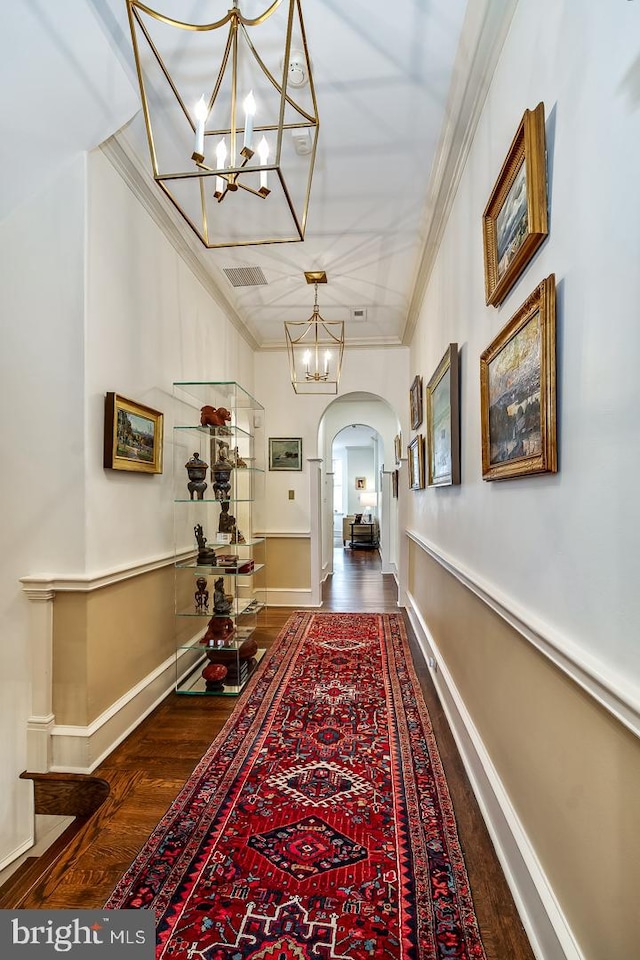 hallway with dark hardwood / wood-style flooring, ornamental molding, and a chandelier