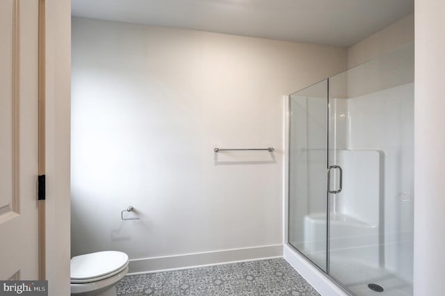 bathroom featuring a shower with door, toilet, and tile flooring