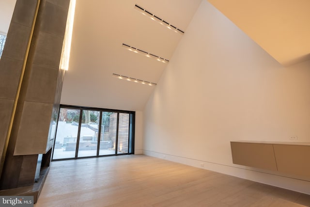 unfurnished living room featuring light wood-type flooring and high vaulted ceiling