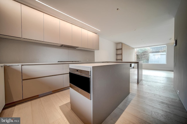 kitchen with a center island, light hardwood / wood-style floors, and wall oven