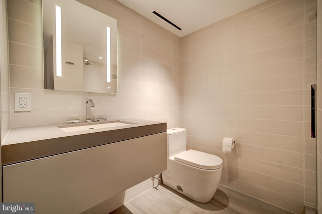 bathroom with toilet, vanity, and tile walls