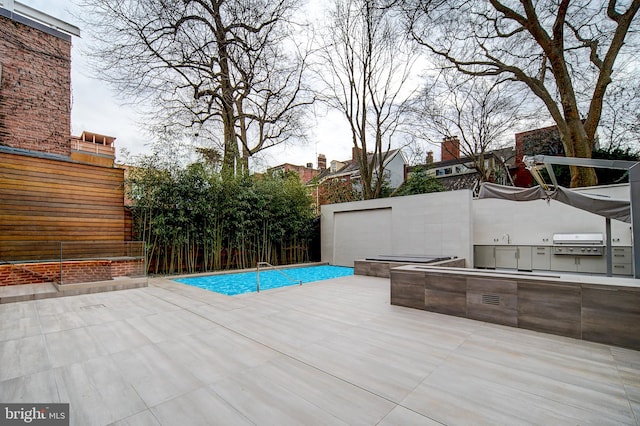 view of pool featuring exterior kitchen, a grill, and a patio