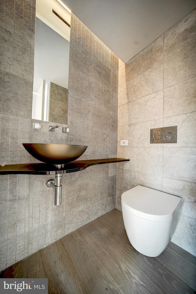 bathroom featuring sink, hardwood / wood-style floors, toilet, and tile walls