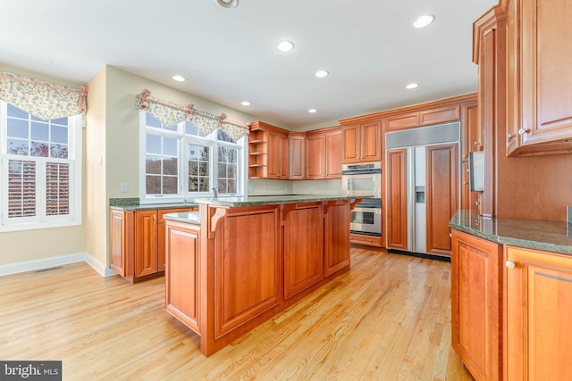 kitchen featuring a center island, a kitchen breakfast bar, paneled built in fridge, double oven, and light hardwood / wood-style floors