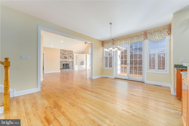 unfurnished dining area featuring a fireplace, light wood-type flooring, and a chandelier