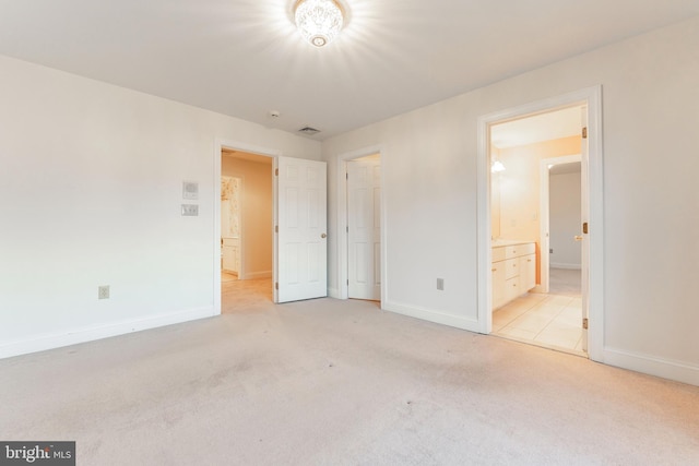 unfurnished bedroom featuring connected bathroom and light colored carpet