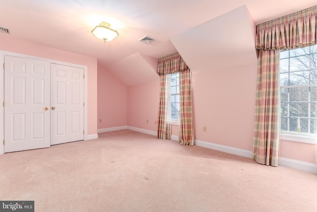 additional living space featuring light carpet and vaulted ceiling