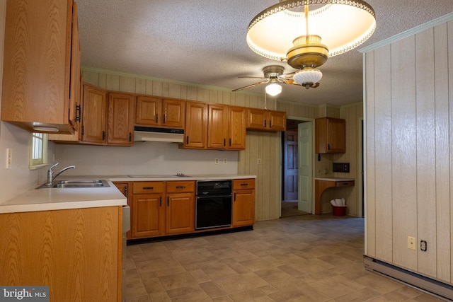 kitchen featuring sink, wooden walls, ceiling fan, ornamental molding, and a textured ceiling