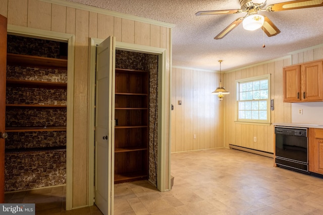 kitchen featuring black dishwasher, hanging light fixtures, a baseboard heating unit, and wood walls