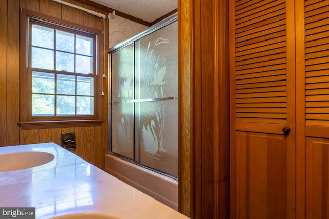 bathroom featuring vanity, a textured ceiling, and enclosed tub / shower combo