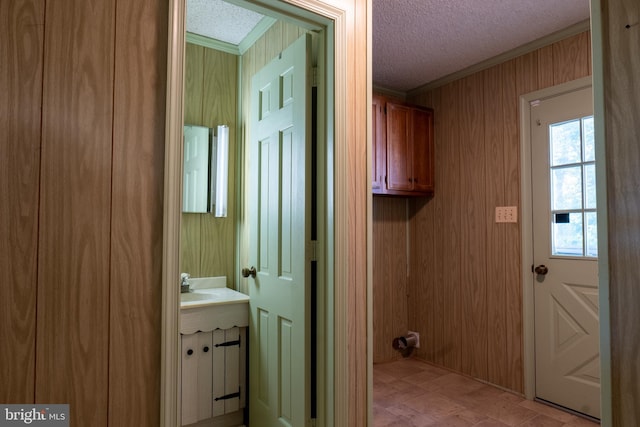 laundry room with crown molding, a textured ceiling, and wooden walls