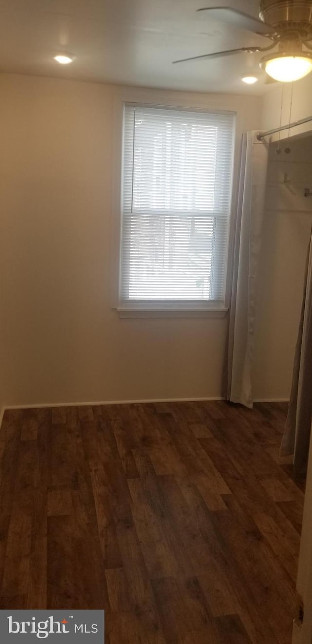 unfurnished bedroom with ceiling fan and dark wood-type flooring