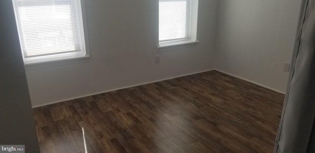 spare room with dark hardwood / wood-style flooring and plenty of natural light