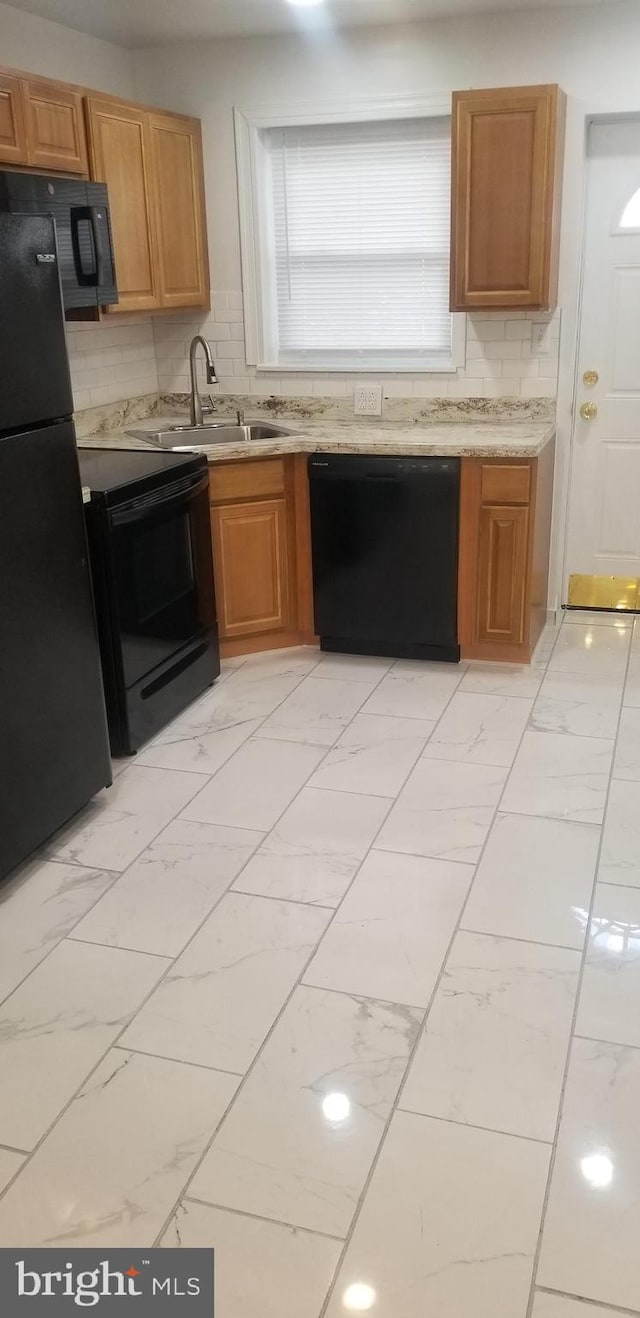 kitchen featuring backsplash, sink, light tile floors, and black appliances