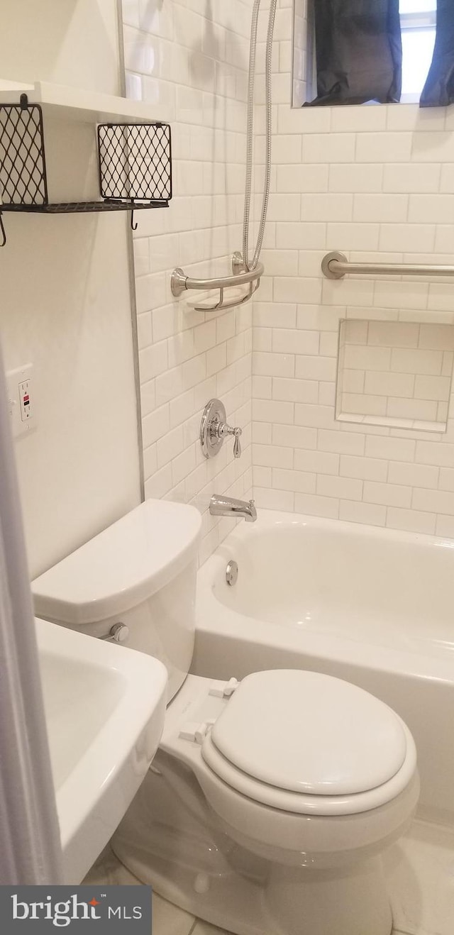 full bathroom with tile flooring, sink, tiled shower / bath, and toilet