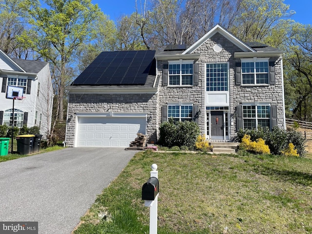 view of front of property with a garage, solar panels, and a front yard