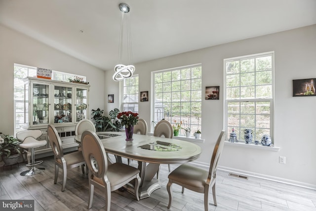 dining room featuring plenty of natural light, light hardwood / wood-style flooring, and vaulted ceiling