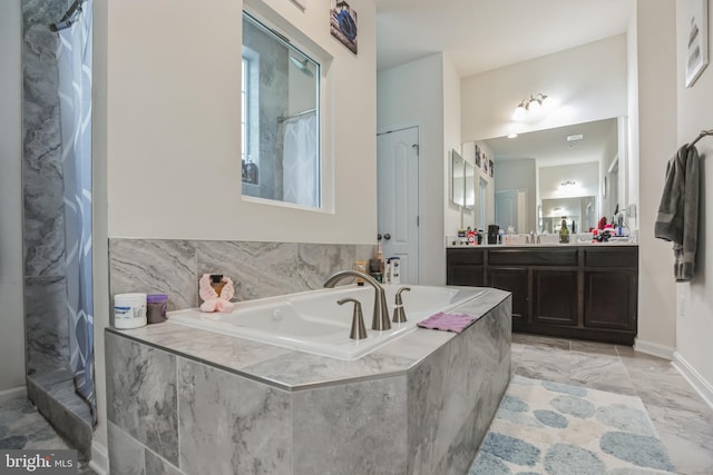 bathroom featuring tiled bath, vanity, and tile flooring