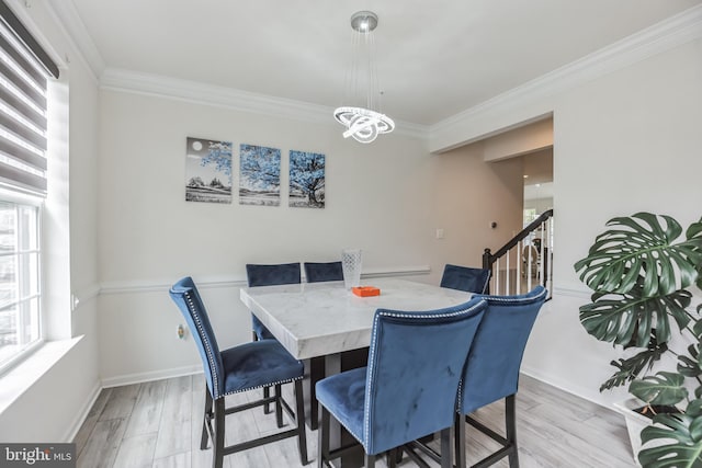 dining space featuring ornamental molding, an inviting chandelier, and light hardwood / wood-style floors