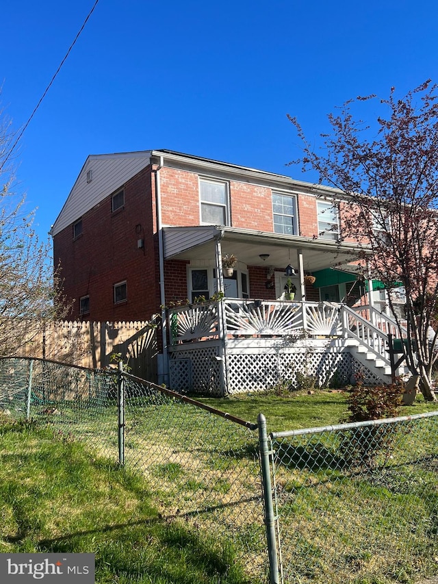 rear view of house with a porch and a yard