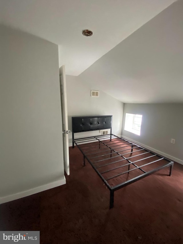 interior space with lofted ceiling and dark carpet