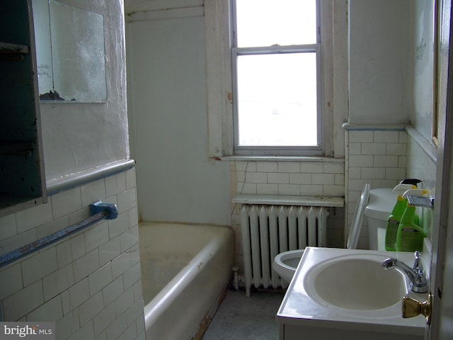 bathroom featuring a tub, radiator heating unit, toilet, vanity, and tile walls