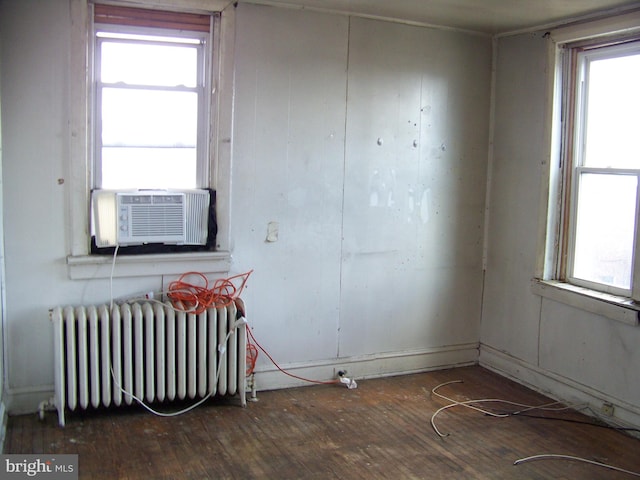 unfurnished room featuring cooling unit, dark hardwood / wood-style flooring, and radiator