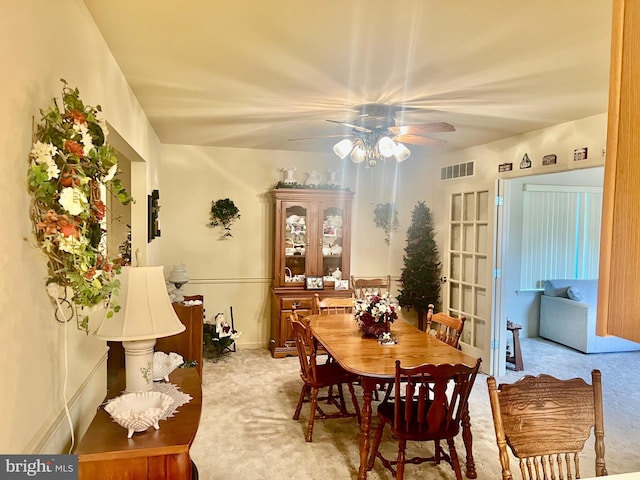 dining space with visible vents, a ceiling fan, and light colored carpet