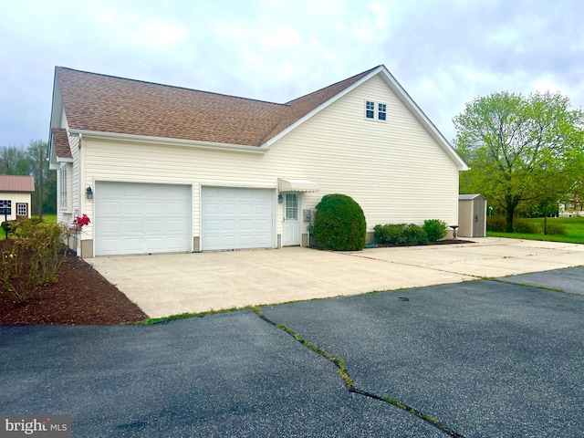 view of side of home featuring a garage, a shingled roof, and concrete driveway