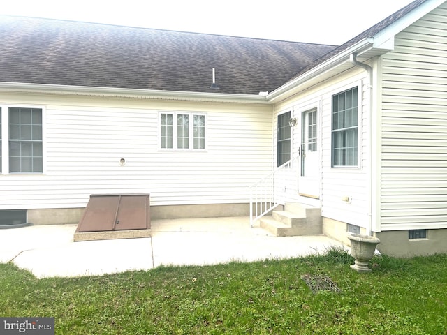 rear view of property featuring entry steps, a yard, and a shingled roof